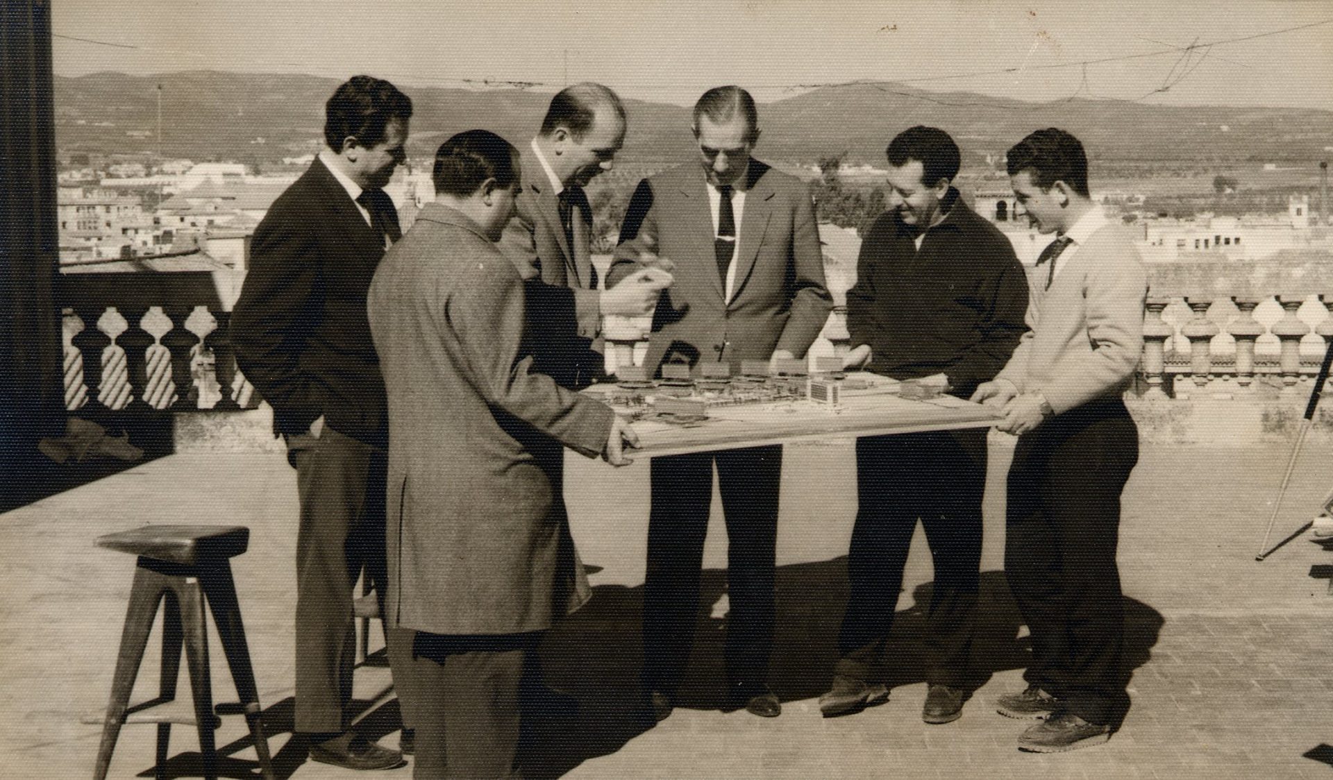 Rafael de La-Hoz Arderius y cinco colaboradores de su estudio, de pie alrededor de una mesa de trabajo en una azotea, en 1962.